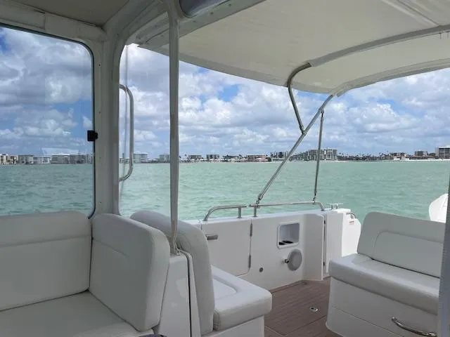 Slide: The Image of 2023 MJM 35z boat interior with white seating, overlooking calm waters and city skyline. - 18