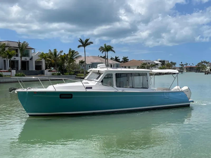 Slide: The Image of 2023 MJM 35z boat on calm water with palm trees and houses in the background. - 2