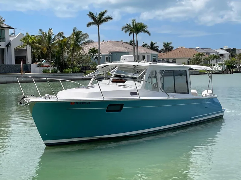 Slide: The Image of 2023 MJM 35z boat on calm water near waterfront homes and palm trees. - 3