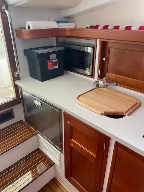 Slide: The Image of 2023 MJM 35z yacht kitchen with wooden cabinets, microwave, and cutting board. - 32