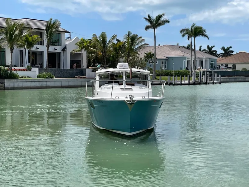 Slide: The Image of 2023 MJM 35z boat cruising in a serene canal near luxury waterfront homes. - 5