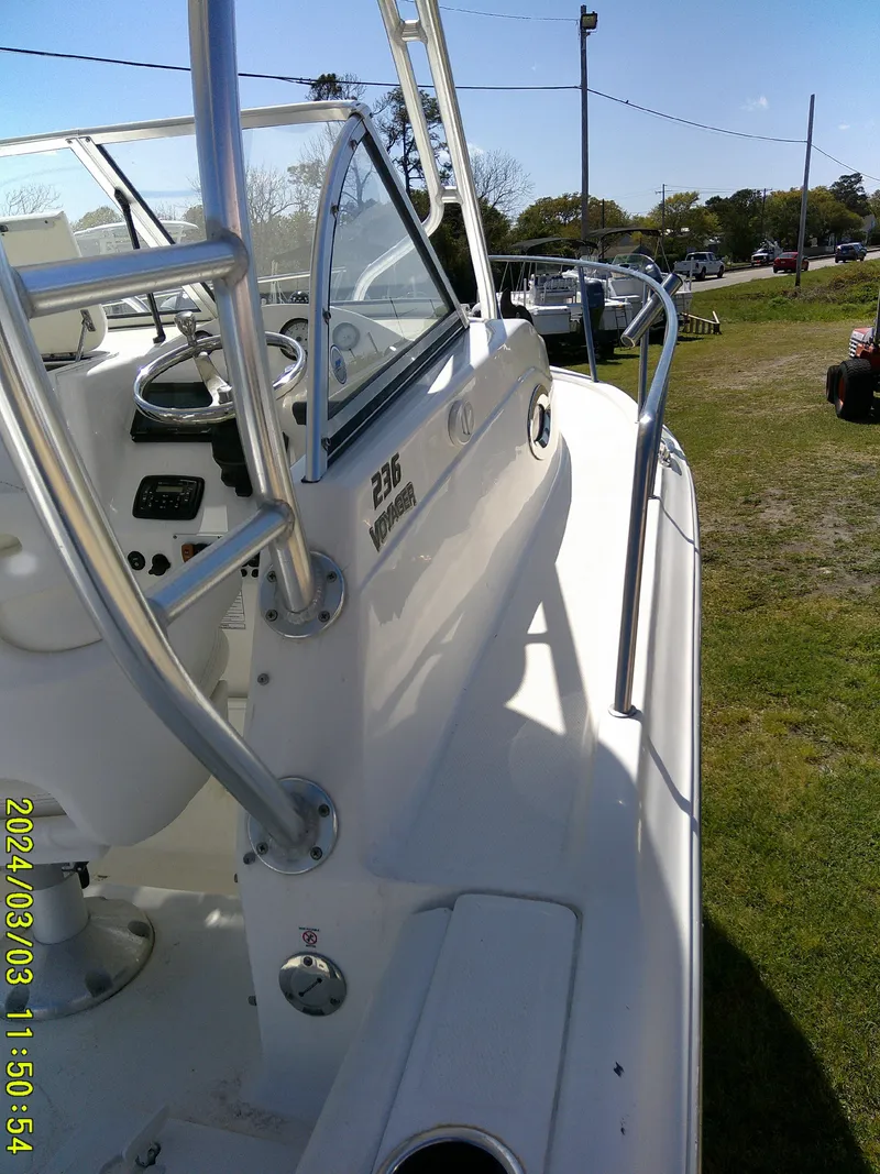 Slide: The Image of 2013 Sea Fox 236 Voyager boat, white exterior, docked on grass, side view. - 18