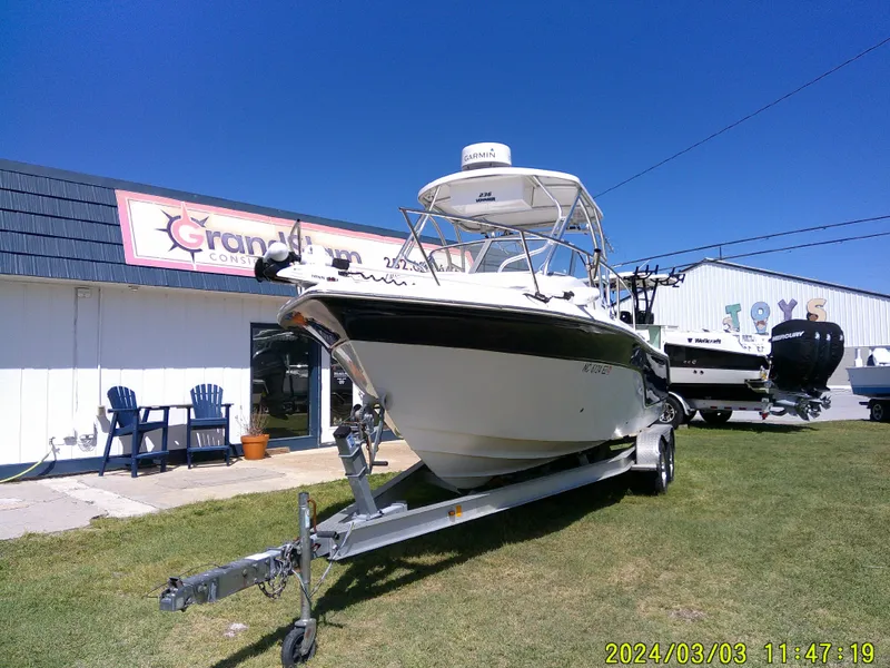 Slide: The Image of 2013 Sea Fox 236 Voyager boat on trailer, parked outside a building under clear blue sky. - 3
