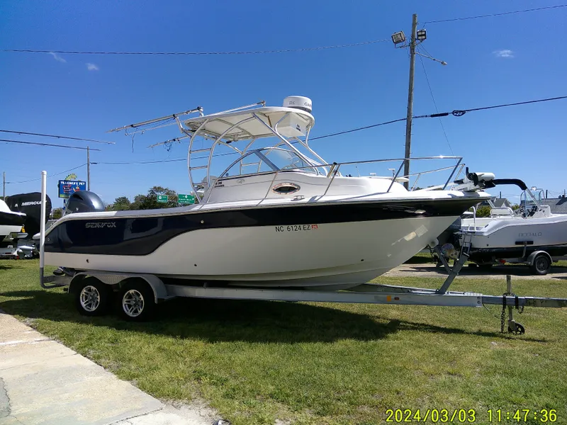 Slide: The Image of 2013 Sea Fox 236 Voyager boat on trailer, parked on grass under clear blue sky. - 5