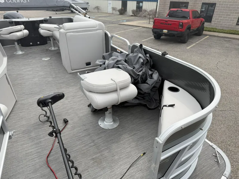 Slide: The Image of 2022 Godfrey Sweetwater 1886 FX pontoon boat interior with seating and equipment in a parking lot. - 9