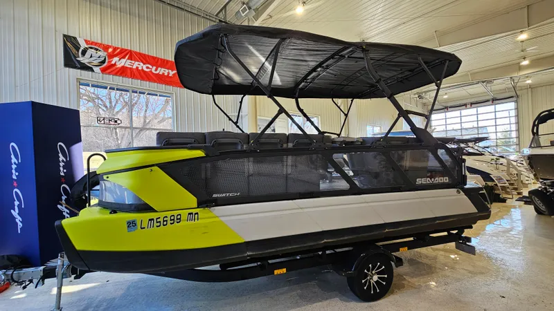 The Image of 2023 Sea-Doo Switch Cruise 21 pontoon boat displayed indoors with canopy and trailer. - 1