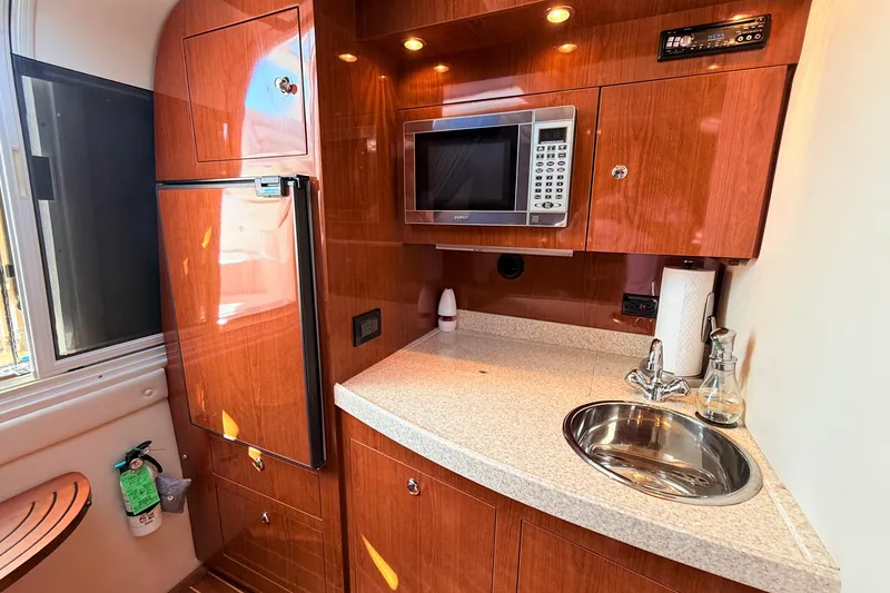 Slide: The Image of 2007 Regal Commodore 3760 IB yacht kitchen with wood cabinetry, microwave, and compact sink. - 14