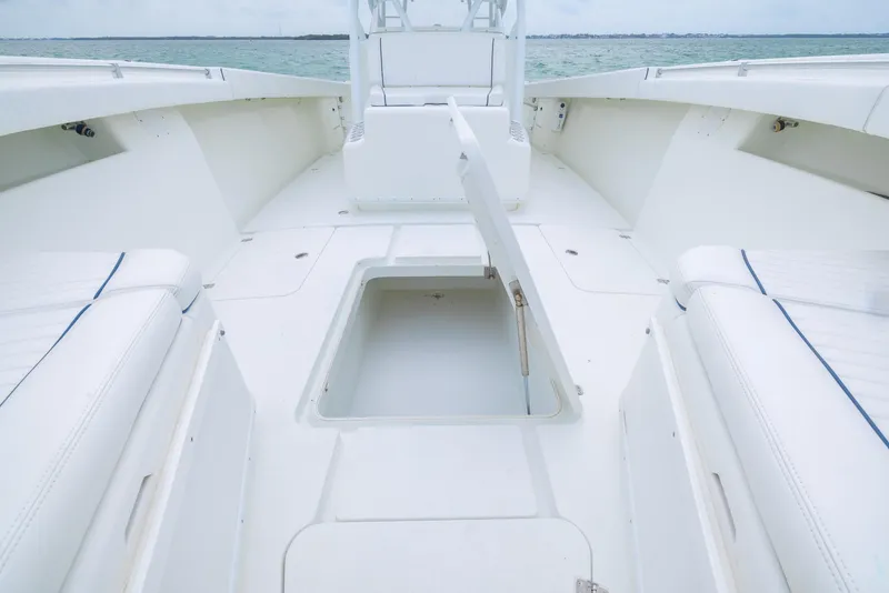 Slide: The Image of 2011 Yellowfin 42 Offshore boat interior with open storage compartment, white seating, and ocean view. - 10