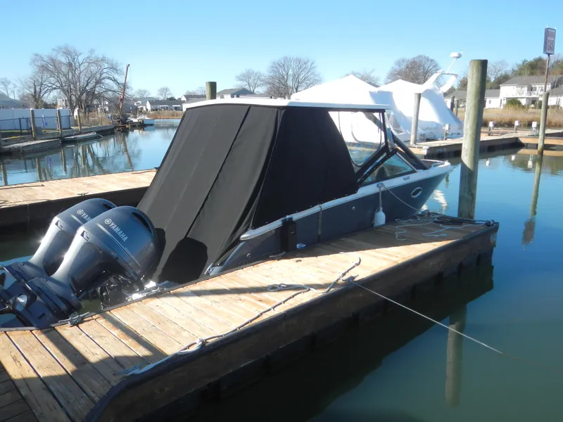 Slide: The Image of 2023 Chaparral 280 OSX boat docked with cover and dual outboard engines. - 2
