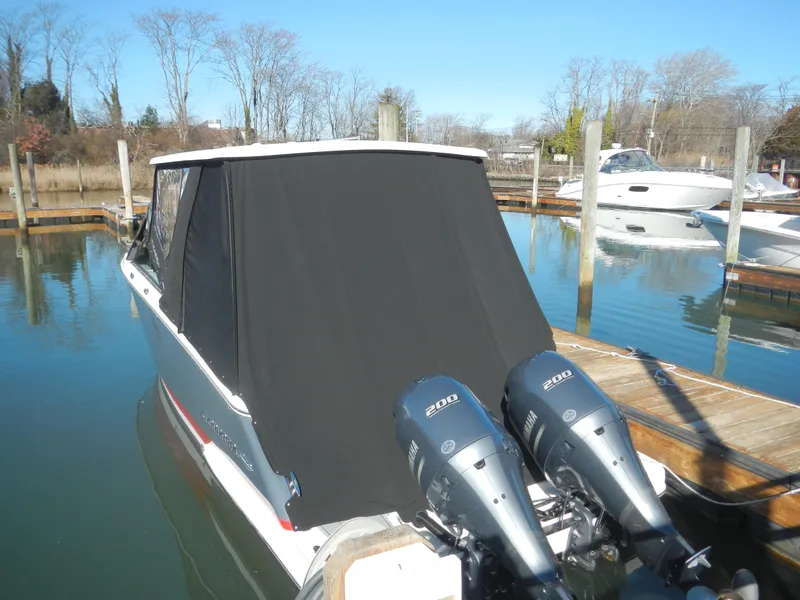 Slide: The Image of 2023 Chaparral 280 OSX boat with dual engines docked, covered in black canvas. - 3