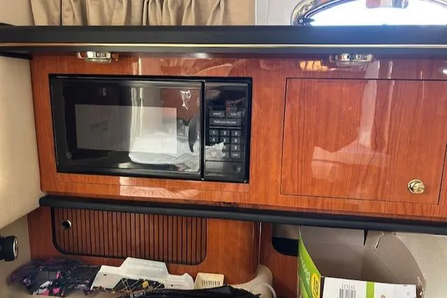 Slide: The Image of Interior of a 2001 Sea Ray 340 Sundancer with a built-in microwave and wooden cabinetry. - 12