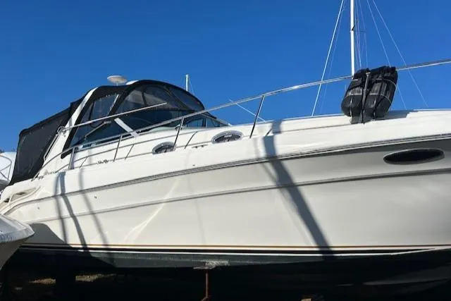 Slide: The Image of 2001 Sea Ray 340 Sundancer boat with black canopy, docked under clear blue sky. - 3