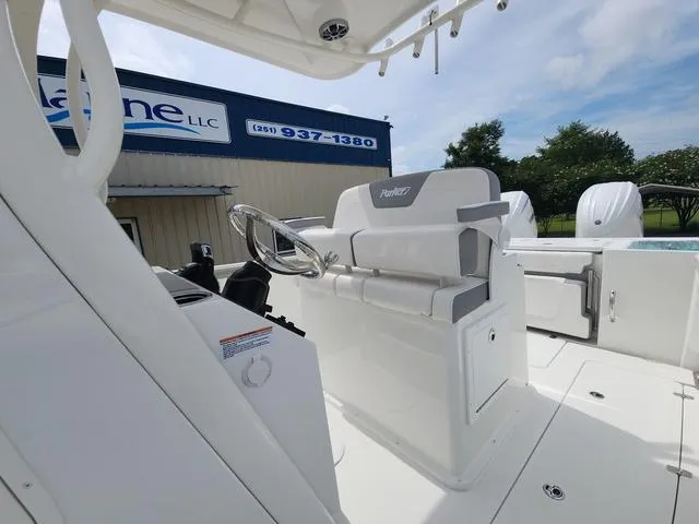 Slide: The Image of 2025 Parker 2600 CC boat interior with steering wheel and seating, near a marine service building. - 18