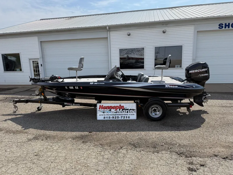 Slide: The Image of 2009 Triton 18 Explorer boat on trailer, parked outside a marine shop. - 0