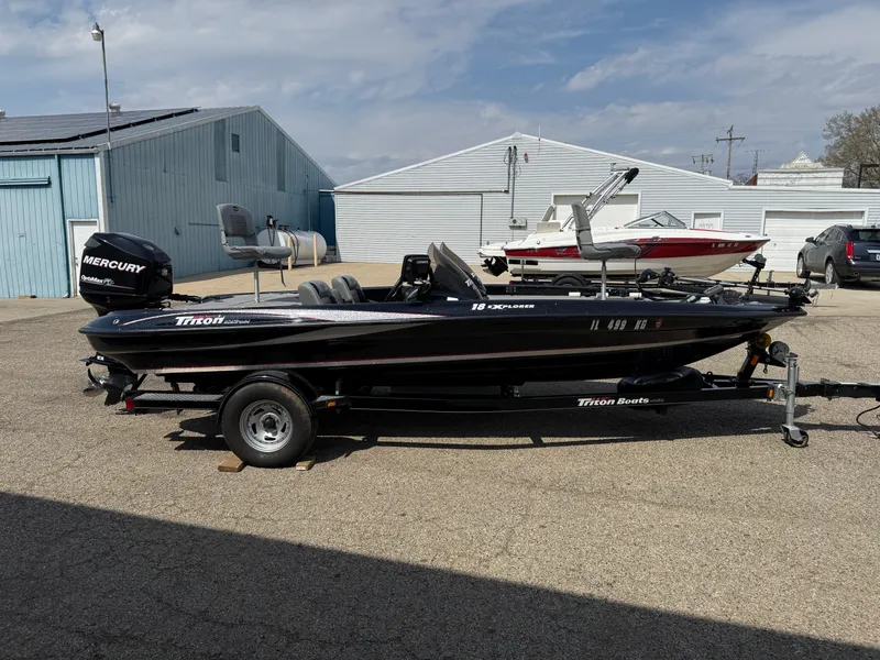 Slide: The Image of 2009 Triton 18 Explorer boat with Mercury engine on trailer, parked outdoors. - 4