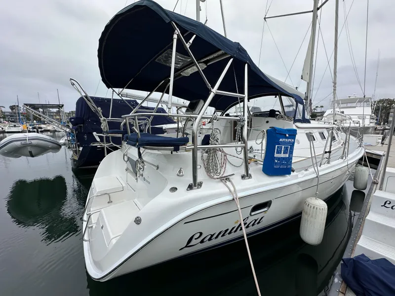 Slide: The Image of 2007 Hunter 44 Deck Salon sailboat docked in marina, featuring blue canopy and sleek design. - 12