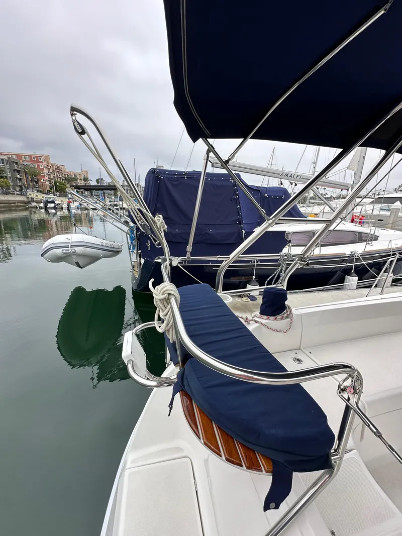 Slide: The Image of 2007 Hunter 44 Deck Salon sailboat docked in a marina, featuring blue canvas covers. - 26