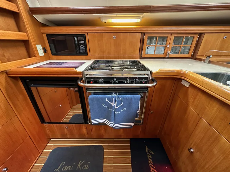 Slide: The Image of 2007 Hunter 44 Deck Salon kitchen with wood cabinetry, stove, microwave, and nautical-themed decor. - 44