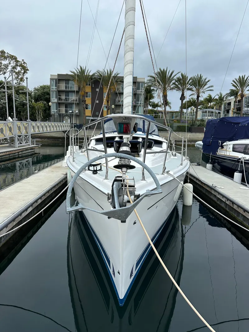 Slide: The Image of 2007 Hunter 44 Deck Salon sailboat docked in marina, surrounded by palm trees and buildings. - 6