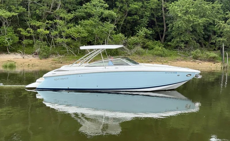 Slide: The Image of 2015 Cobalt 302 boat on calm water near a forested shoreline. - 1