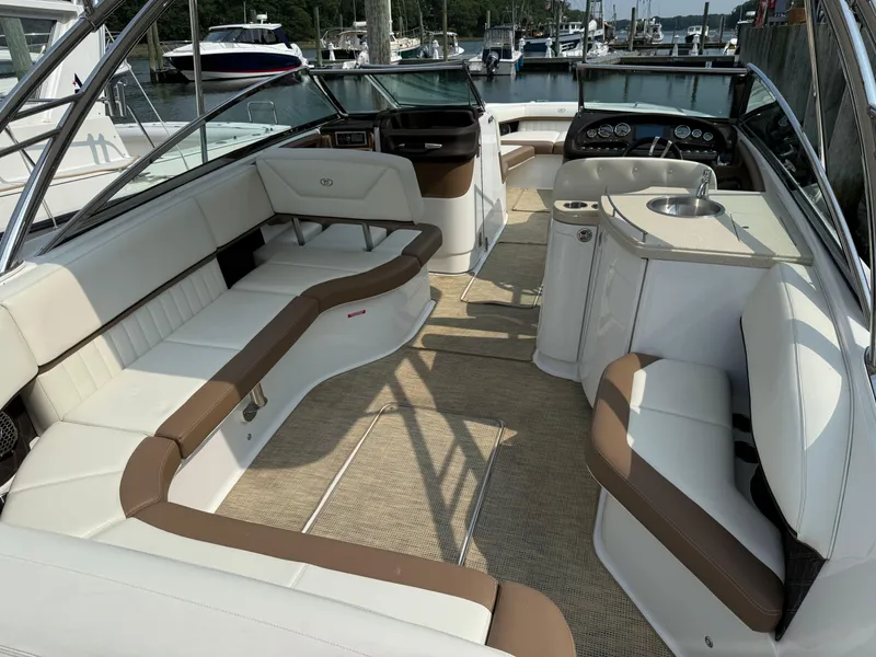 Slide: The Image of 2015 Cobalt 302 boat interior with white and brown seating, docked at a marina. - 10