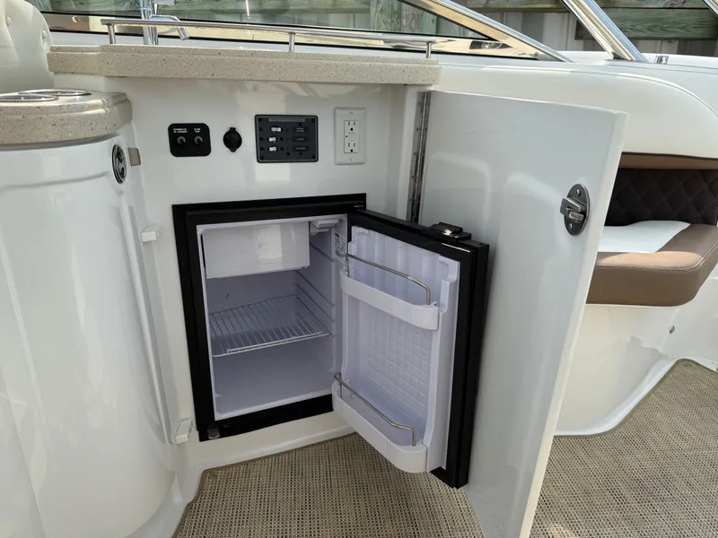 Slide: The Image of Open mini fridge on 2015 Cobalt 302 boat, showcasing interior storage and control panel. - 13