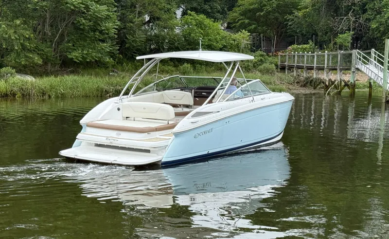 Slide: The Image of 2015 Cobalt 302 boat on a calm river near lush greenery. - 2