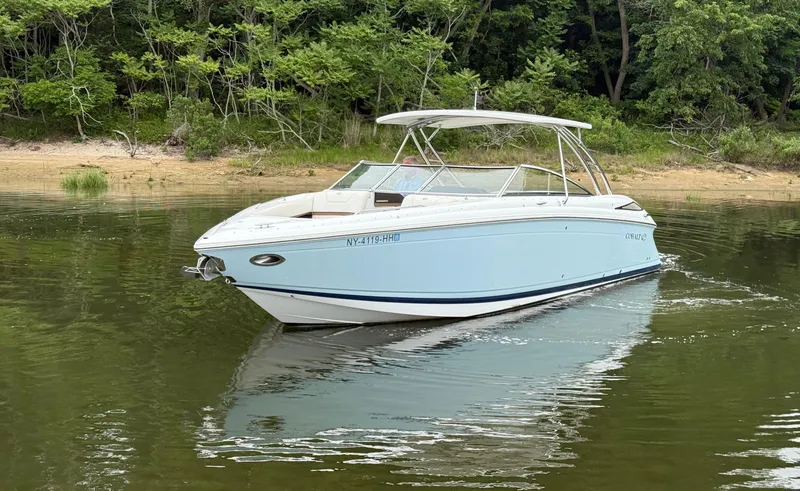 Slide: The Image of 2015 Cobalt 302 boat cruising on a calm lake near a forested shoreline. - 3