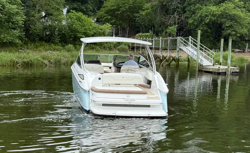 Slide: The Image of 2015 Cobalt 302 boat navigating a calm river near a dock and lush greenery. - 7