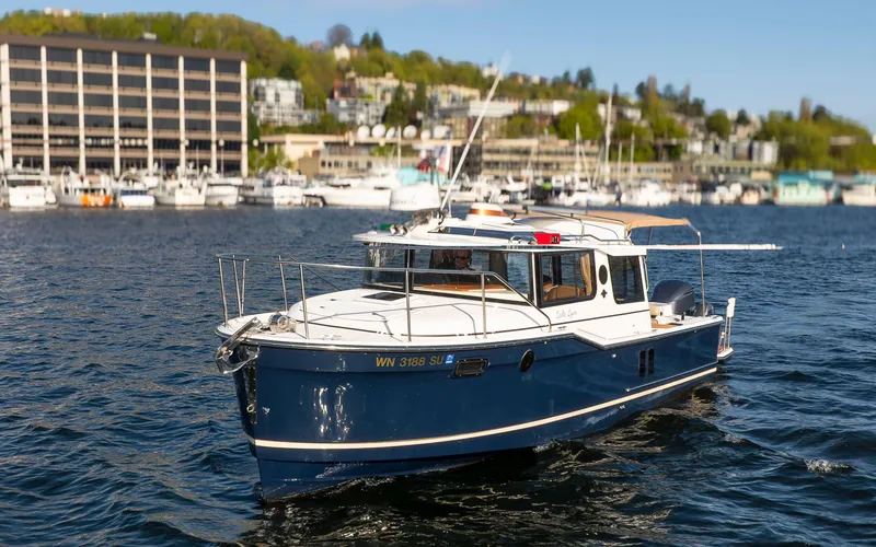 Slide: The Image of 2020 Ranger Tugs R-27 boat on water, with marina and buildings in background. - 14