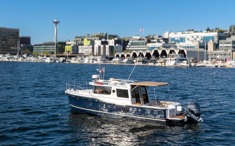 Slide: The Image of 2020 Ranger Tugs R-27 boat on water with cityscape and Space Needle in background. - 2