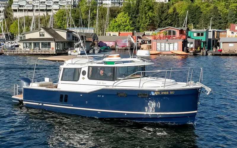 Slide: The Image of 2020 Ranger Tugs R-27 boat cruising on a scenic waterfront with docks and greenery. - 21