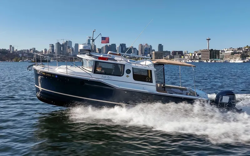 Slide: The Image of 2020 Ranger Tugs R-27 cruising on water with city skyline in background. - 23