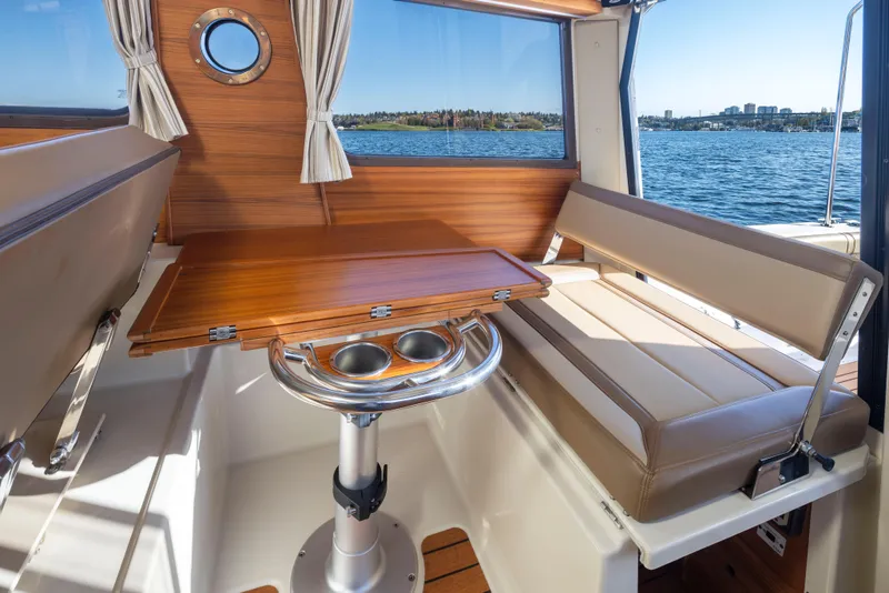 Slide: The Image of 2020 Ranger Tugs R-27 interior with wooden table, seating, and scenic water view. - 24