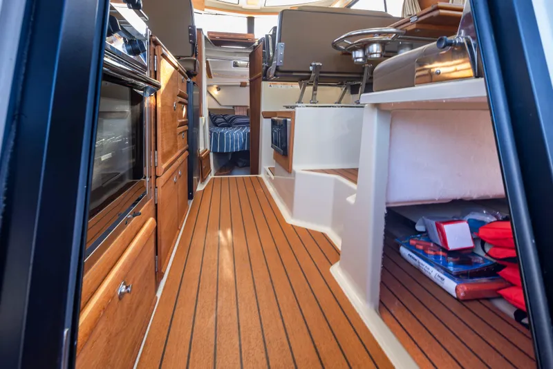 Slide: The Image of Interior of 2020 Ranger Tugs R-27 boat with wood flooring and compact kitchen area. - 26