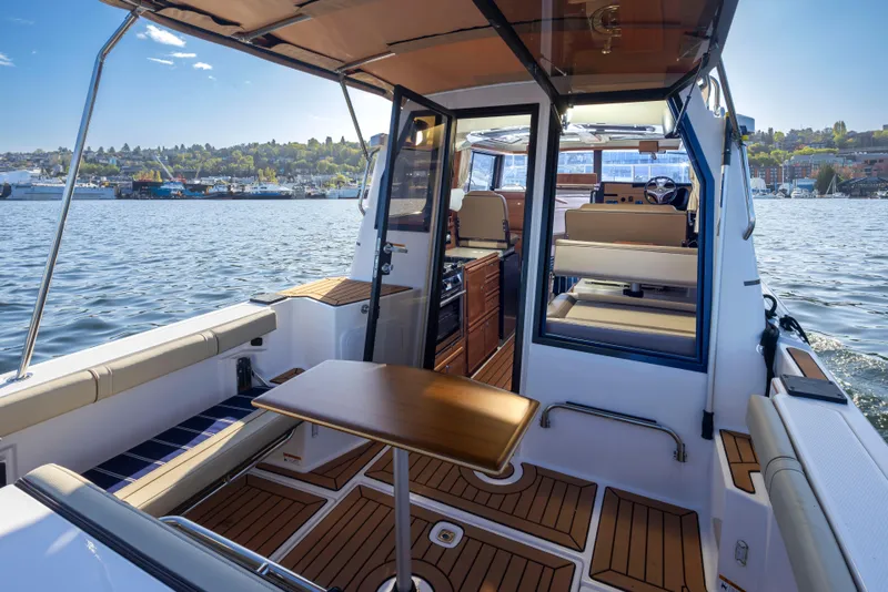Slide: The Image of 2020 Ranger Tugs R-27 boat interior with seating and table on a sunny day. - 27