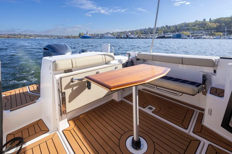 Slide: The Image of 2020 Ranger Tugs R-27 boat deck with wooden table, scenic waterfront view. - 29