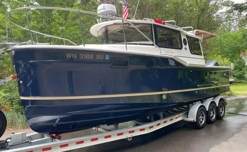 Slide: The Image of 2020 Ranger Tugs R-27 boat on trailer, parked outdoors with lush greenery background. - 32