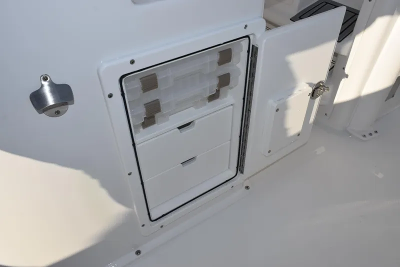 Slide: The Image of 2025 Sea Hunt Gamefish 25 boat storage compartment with open door and organized drawers. - 19
