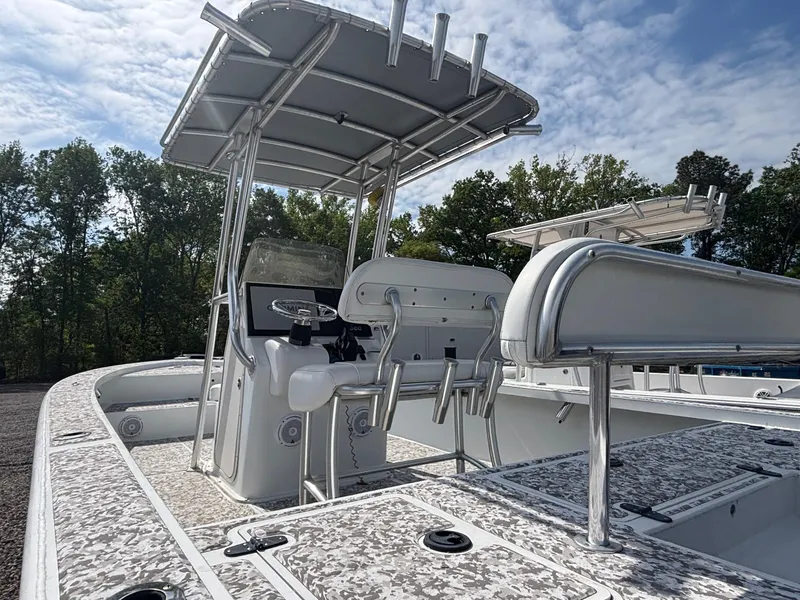 Slide: The Image of 2018 Cast & Blast 22 Kings Bay boat with T-top and seating, set against a wooded backdrop. - 8
