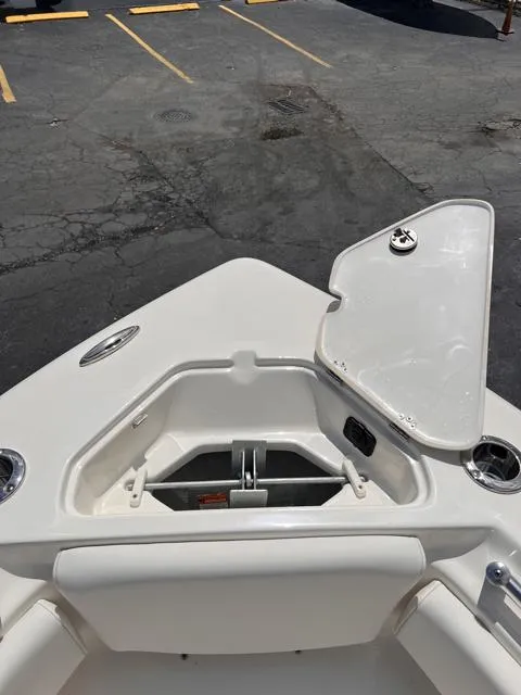 Slide: The Image of 2025 Key West 219 FS boat anchor compartment with open hatch, docked on asphalt. - 27