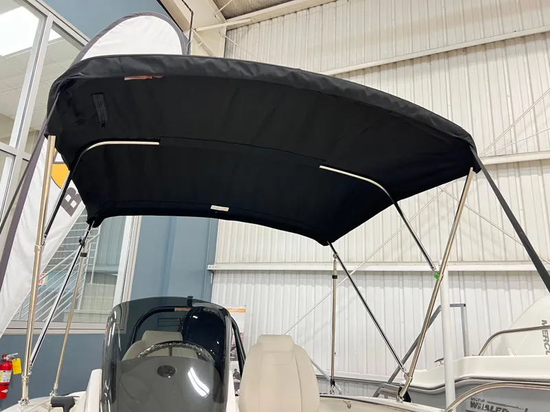 Slide: The Image of 2025 Boston Whaler 160 Super Sport with black canopy in showroom. - 8