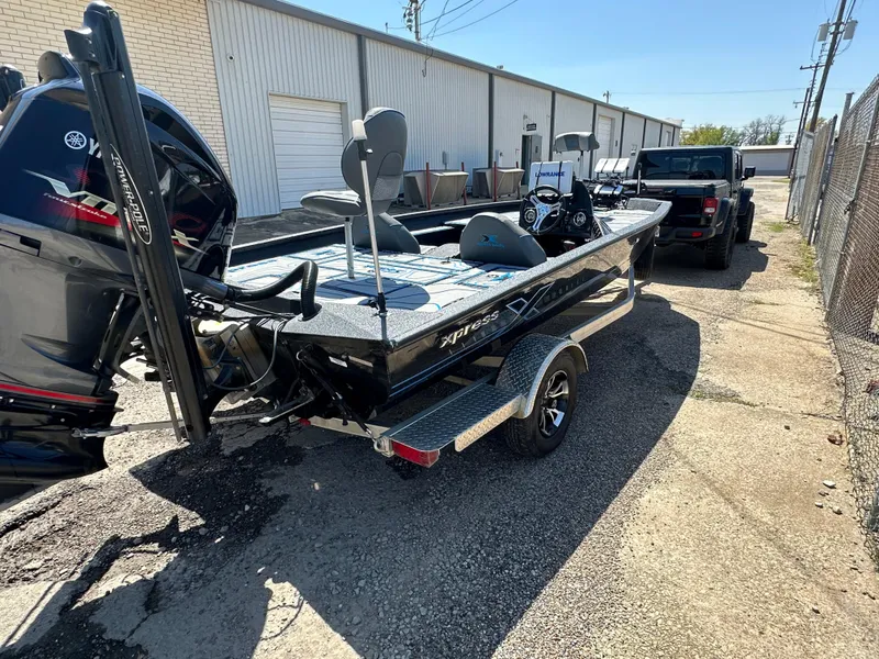 Slide: The Image of 2021 Xpress X19 Pro boat on trailer, parked outdoors near industrial building. - 2