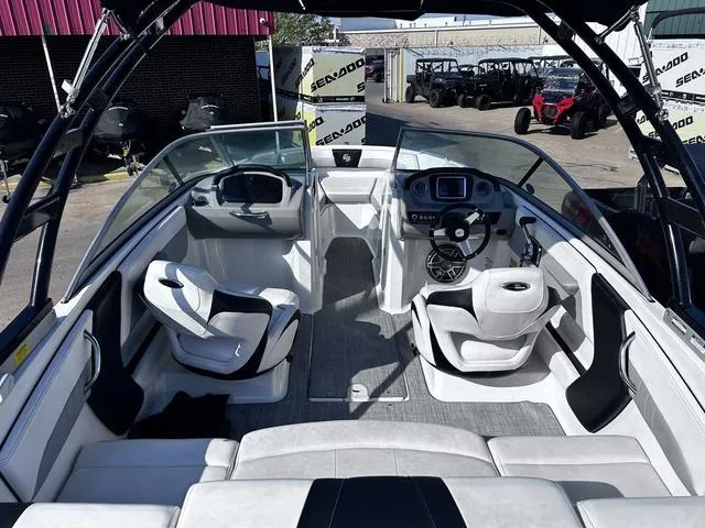 Slide: The Image of 2020 Chaparral 21 Surf boat interior with modern seating and dashboard, parked near Sea-Doo vehicles. - 5