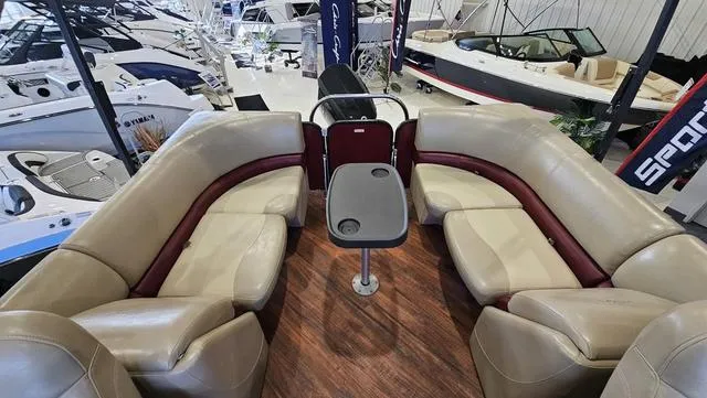 Slide: The Image of 2017 Manitou Aurora 25 LE pontoon boat interior with beige seating and central table. - 12