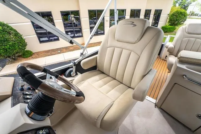 Slide: The Image of Captain's chair on 2014 Bennington 2550 RBR boat, featuring plush beige upholstery and steering wheel. - 23