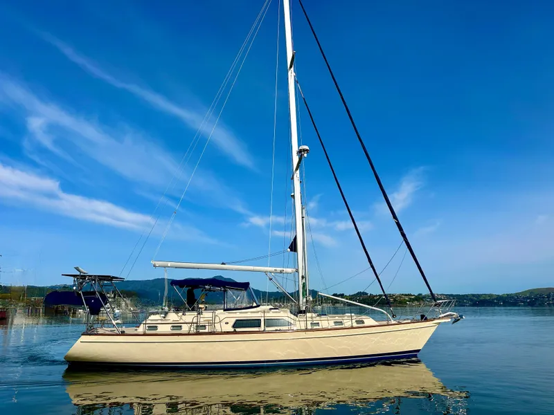 Slide: The Image of 2006 Island Packet 485 Center Cockpit sailboat on calm water under clear blue sky. - 0