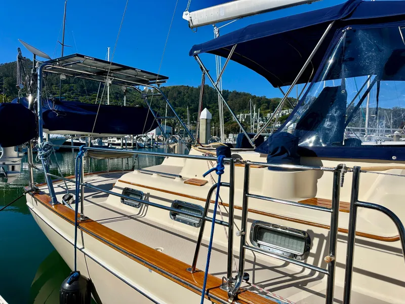 Slide: The Image of 2006 Island Packet 485 Center Cockpit sailboat docked in a marina, featuring blue canopies. - 12