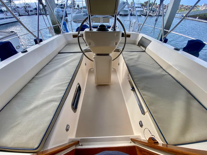 Slide: The Image of 2006 Island Packet 485 Center Cockpit sailboat with spacious seating and steering wheel, docked at marina. - 15