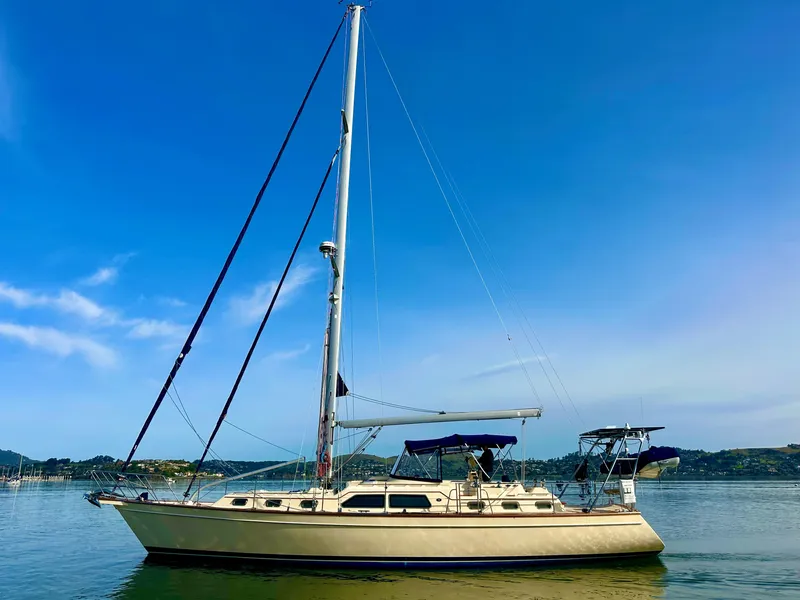 Slide: The Image of 2006 Island Packet 485 Center Cockpit sailboat on calm water under clear blue sky. - 2